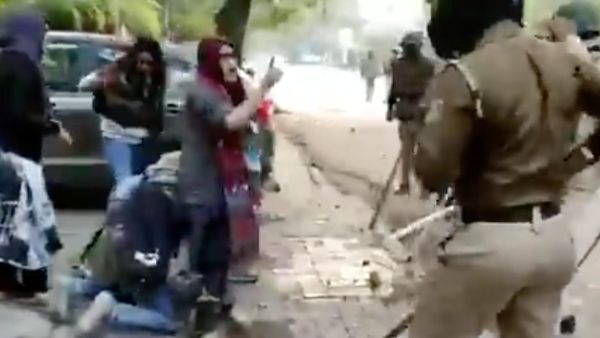 The video shows several police officers in riot gear hitting a man with sticks and dragging him to the ground. 