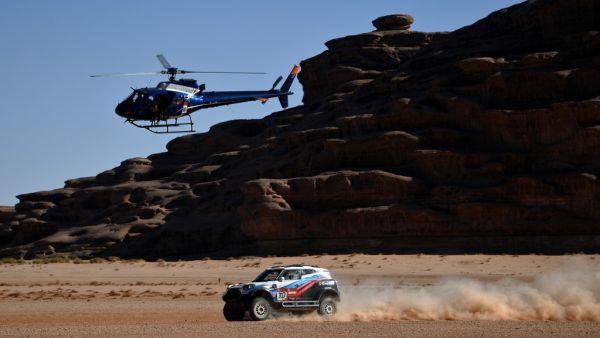 A helicopter flies as Russia's driver Vladimir Vasilyev and co-driver Vitaly Yevtyekhov of Ukrainia steer their Mini during the Stage 3 of the Dakar 2020 around Neom, Saudi Arabia