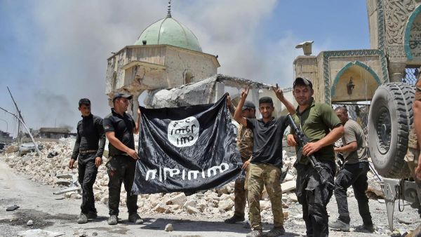 Iraqi Counter-Terrorism Service making the victory gesture as members hold the black ISIS flag upside down outside the destroyed Al-Nuri Mosque. (Fadel Senna / AFP)