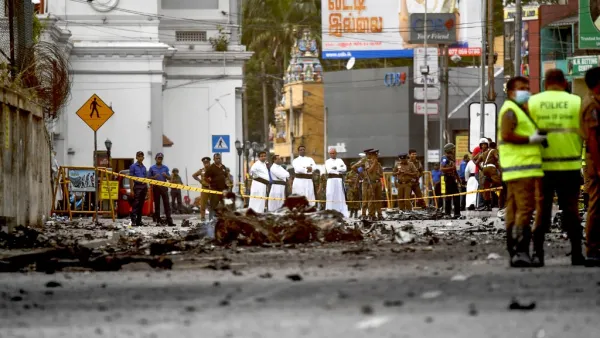 Sri Lankan priests look at the debris of a car after it explodes when police tried to defuse a bomb near St. Anthony's Shrine in Colombo on April 22, 2019. (AFP)