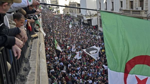 Algerians wave a national flag from a balcony as they watch anti-government demonstrators march in the capital Algiers on December 6, 2019, ahead of the presidential vote scheduled for December 12.  (AFP/ File Photo)