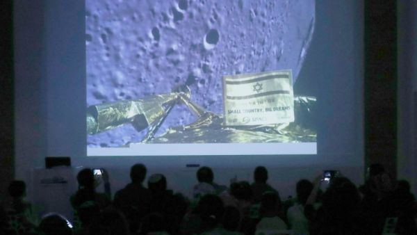 People watch a screen showing a picture taken by the camera of the Israel Beresheet spacecraft of the moon surface as the craft approaches and before it crashed during the landing at the "Planetaya Planetarium" in the Israeli city of Netanya. (JACK GUEZ / AFP)