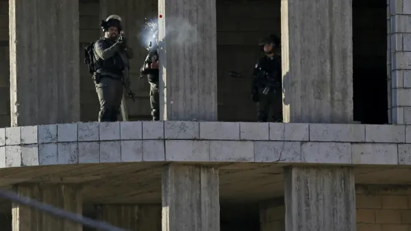 An Israeli soldier fires a tear gas canister at Palestinian stone throwers following a raid in the West Bank city of Ramallah. (AFP)
