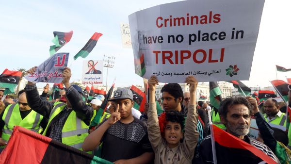 Libyans carry placards during a demonstration with yellow vests ("gilets jaunes") against strongman Khalifa Haftar in the capital Tripoli's Martyrs Square on April 19, 2019. (Mahmud TURKIA / AFP)