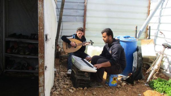 Two young men play instruments together in Azraq camp. The photo was part of an exhibition depicting teenage refugees’ aspirations and realities (Photo courtesy of Plan International)