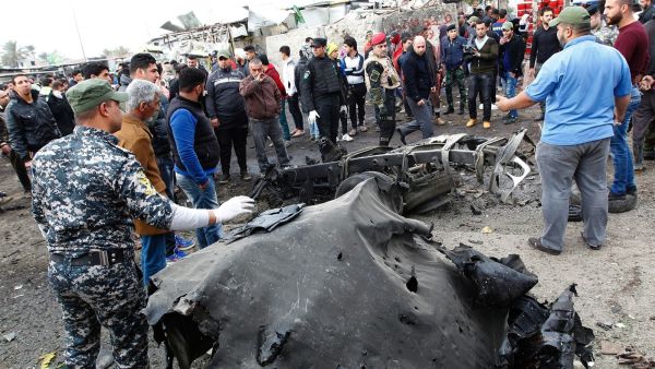 Security forces and civilians surround a destroyed car at the site of Monday's bombing. ( SABAH ARAR/Getty-AFP )