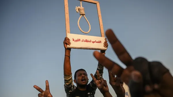 A Sudanese protester holds a hanging rope as others flash victory sign during a protest outside the army headquarters in the capital Khartoum on April 21, 2019. (AFP/ File)