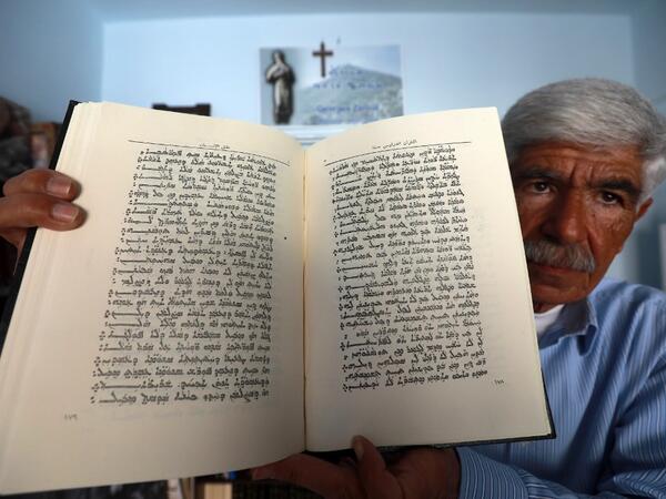 George Zaarour, a specialist in the Aramaic language, shows a book written in the Aramaic script in the Syrian mountain village of Maalula, in the Damascus region on May 13, 2019. LOUAI BESHARA / AFP