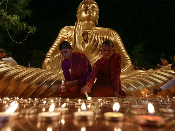 Young Buddhist monks light candles at the bottom of a giant statue of Buddha on the eve of Buddha Purnima, a holiday traditionally celebrated for Buddha's birthday also known as Vesak celebrations, in Bhopal on 17 May, 2019. Gagan Nayar / AFP