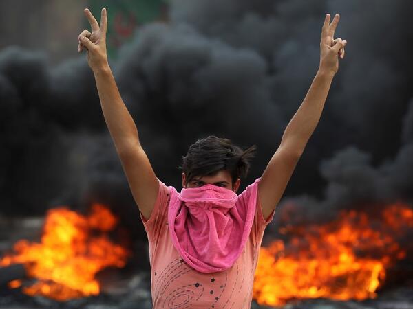 An Iraqi protester flashes the v-sign during a demonstration against state corruption, failing public services and unemployment in the Baladiyat district of the capital Baghdad on October 2, 2019. Iraq's president and the United Nations urged security forces to show restraint after two protesters were killed in clashes with police that other top officials blamed on "infiltrators." AHMAD AL-RUBAYE / AFP
