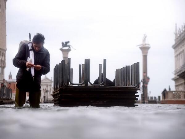 A man prepares a cigarette as he walks in the water of the flooded St. Mark's Square, on November 15, 2019 in Venice, two days after the city suffered its highest tide in 50 years. Flood-hit Venice was bracing for another exceptional high tide on November 15, as Italy declared a state of emergency for the UNESCO city where perilous deluges have caused millions of euros worth of damage. Filippo MONTEFORTE / AFP