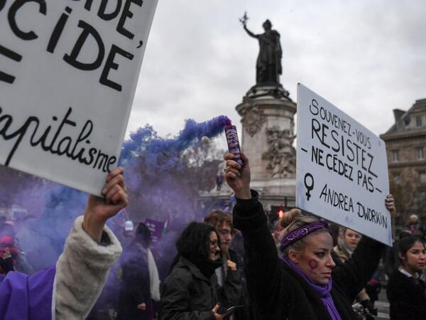 A woman holds a flare and a placard reading "Remember, resist, do not give in" during a protest to condemn violence against women, on November 23, 2019, in Paris. Alain JOCARD / AFP