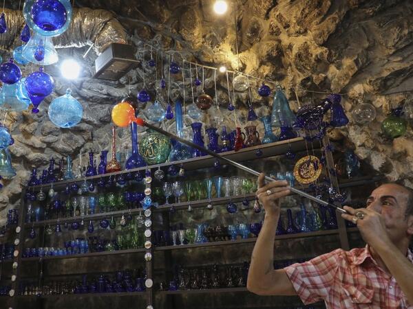 A Palestinian man blows molten glass into a Christmas ornament at his glass factory in the southern West Bank city of Hebron, on December 15, 2019. HAZEM BADER / AFP