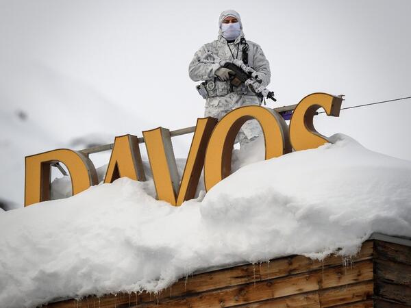 In this file photo taken on January 21, 2019, policeman wearing camouflage clothing stands on the rooftop of a hotel, next to letters covered in snow reading 'Davos', near the Congress Centre ahead of the World Economic Forum (WEF) annual meeting in Davos, eastern Switzerland. The World Economic Forum 50th Annual Meeting in Davos is held from January 21 to 24, 2020. Fabrice COFFRINI / AFP
