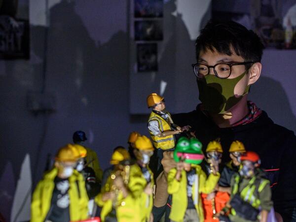 This picture taken on January 14, 2020 shows figurine enthusiast Charlie, who asked to use a pseudonym, posing with 1:6 scale action figures depicting characters involved in the Hong Kong protests, following an interview with AFP in Hong Kong. Intricately detailed Hong Kong protester figurines have become the latest must-have collectables as toy stores recreate the pro-democracy movement's street battles with police in their shop displays.  Philip FONG / AFP