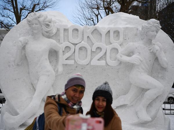 A couple poses for a selfie in front of a snow sculpture with a motif of the upcoming Tokyo 2020 Olympic Games, during the Sapporo Snow Festival in Sapporo on February 4, 2020. The snow festival, which opened January 31 in the capital of Hokkaido in northern Japan. CHARLY TRIBALLEAU / AFP