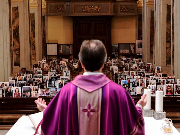 Don Giuseppe Corbari, parson of the Church of Robbiano, holds Sunday mass as he looks towards selfie photographs sent in by his congregation members and glued to empty pews in Giussano on March 22, 2020. AFP