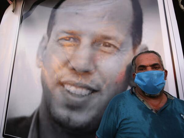 An Iraqi demonstrator wearing a face mask to protect agaisnt the Covid-19 coronavirus, attends a symbolic funeral for slain Iraqi jihadism expert Hisham al-Hashemi, who was shot dead yesterday outside his house in the Iraqi capital, on July 7, 2020 at Baghdad's Tahrir square. The killing of the 47-year-old prominent expert has stirred fears Iraq is entering a dark and violent phase, as boiling tensions between pro-Iran factions and the government reach new heights. AHMAD AL-RUBAYE / AFP