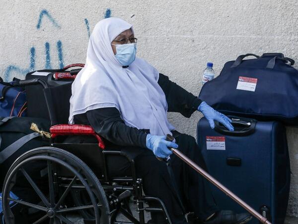 A Palestinian woman waits next to her luggage to leave Rafah border crossing with Egypt after months of closure due to the coronavirus pandemic in the southern Gaza Strip, on August 11, 2020. SAID KHATIB / AFP
