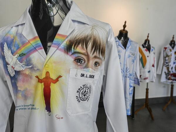 View of white coats used by doctors fighting against COVID-19 and decorated by Panamanian artists, in Panama City, on September 26, 2020. More than 20 doctor's coats fighting against COVID-19 that were disinfected and painted by Panamanian artists will be auctioned off from October 1 to 4. The funds will go to 20 health centers. Luis ACOSTA / AFP