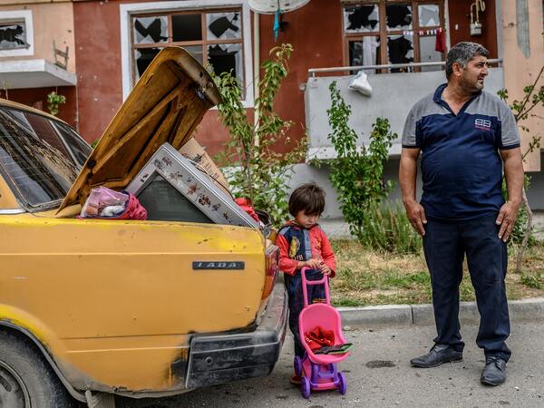 A man stands with his kid by a car outside a damaged apartment building after the family took their last belongings from their flat during a ceasefire during a military conflict between Armenia and Azerbaijan over the breakaway region of Nagorno-Karabakh, in the town of Terter, Azerbaijan, on October 10, 2020. Armenia and Azerbaijan traded accusations of new attacks on October 10 in breach of a ceasefire deal to end nearly two weeks of heavy fighting over the disputed Nagorno-Karabakh region. Bulent Kilic /