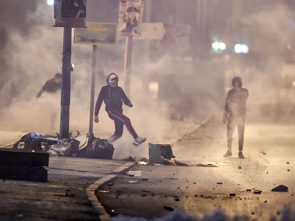 Protesters stand amidst fumes as they block a street during clashes with security forces in the Ettadhamen city suburb on the northwestwern outskirts of Tunisia's capital Tunis on January 17, 2021, amidst a wave of nightly protests in the North African country. FETHI BELAID / AFP