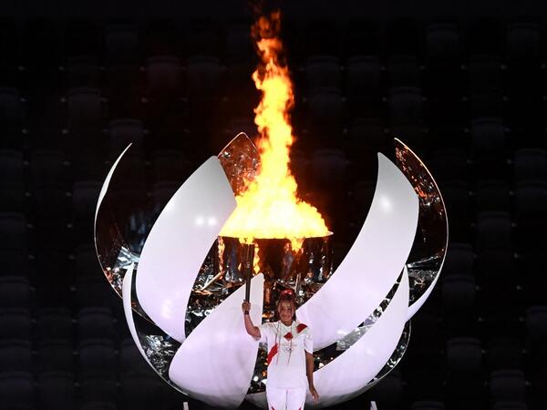 Japanese tennis player Naomi Osaka holds the Olympic Torch after lighting the flame of hope in the Olympic Cauldron during the opening ceremony of the Tokyo 2020 Olympic Games, at the Olympic Stadium, in Tokyo
