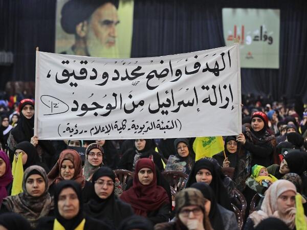 Supporters of Lebanese Hezbollah Leader gather as he delivers a televised speech during a ceremony held by the Shiite party in the capital Beirut, commemorating the party's killed leaders, on Feb. 16, 2018. The writing in Arabic reads: "The goal is clear, specific and precise...the removal of Israel from existence." 
(JOSEPH EID / AFP)
