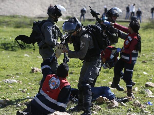 Palestinian Civil Defence volunteers scuffle on Mar.12, 2018 in the West Bank town of Birzeit, near Ramallah, with Israeli soldiers as they attempt to give aid to an injured Palestinian demonstrator during a protest by students of the Birzeit University against the arrest of the the head of Palestinian student council by an Israeli undercover commando. 
(ABBAS MOMANI / AFP)