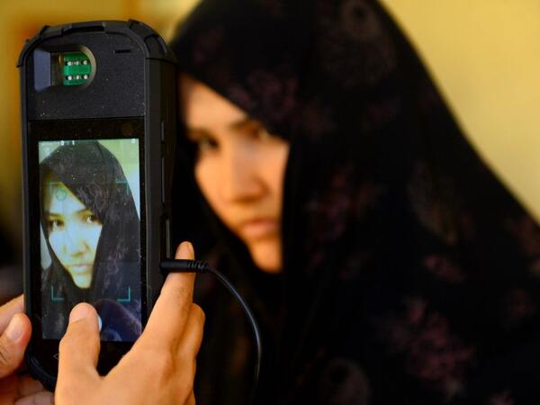 An Afghan Independent Election Commission (IEC) official scans a voter's face with a biometric device at a polling centre for the country's legislative election in Herat province on October 20, 2018. 
HOSHANG HASHIMI / AFP