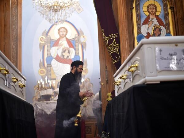 An Coptic priest blesses the coffins of victims, killed in an attack a day earlier, during an early morning ceremony at the Prince Tadros church in Egypt's southern Minya province, on November 3, 2018. 
MOHAMED EL-SHAHED / AFP