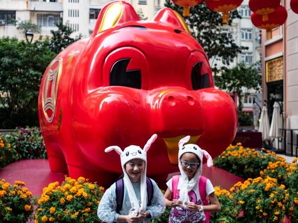 Children in animal hats pose in front of a giant pig installation ahead of the Lunar New Year in Hong Kong on February 4, 2019. 
Philip FONG / AFP