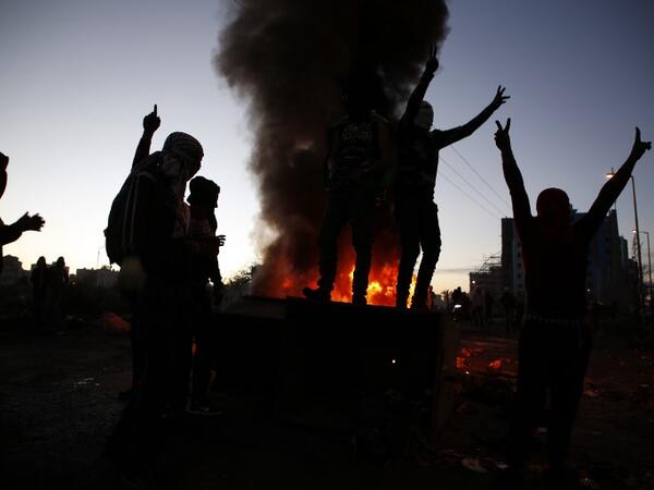 Palestinian demonstrators gesture as they stand on a trash container during clashes with Israeli forces near an Israeli checkpoint in the West Bank city of Ramallah.
(ABBAS MOMANI / AFP)