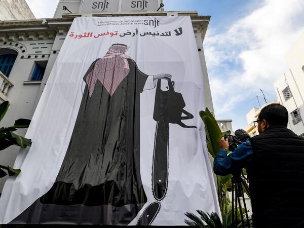 This picture taken on November 26, 2018 shows a giant banner hanging at the headquarters of Tunisia's Journalists Union in the capital Tunis depicting a cartoon of Saudi Crown Prince Mohammed bin Salman holding a chainsaw with a caption above reading in Arabic "no to the desecration of Tunisia, the land of the revolution". 
FETHI BELAID / AFP