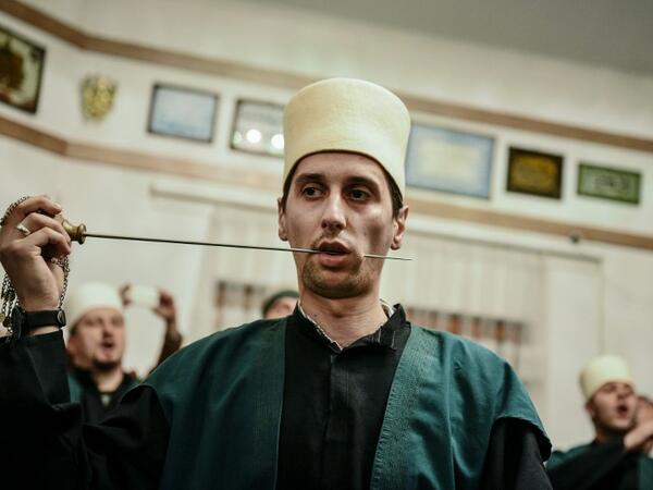 A Kosovo Dervish, an adept of Sufism, a mystical form of Islam, pierces his cheek with a needle during a ceremony in a prayer room in Gjakova
Gent SHKULLAKU / AFP