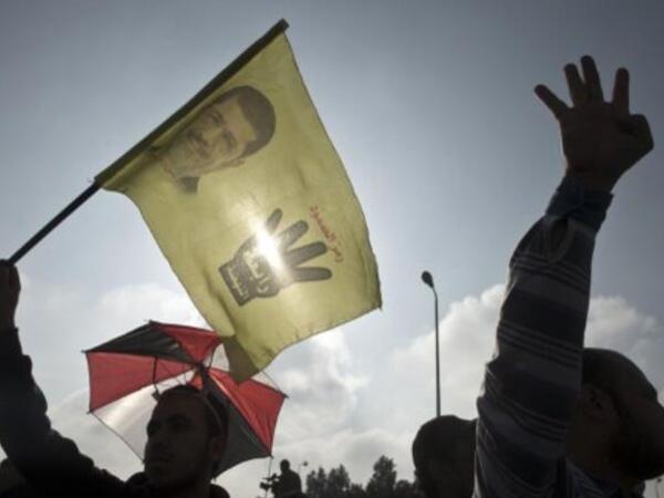 A supporter of the ousted Egyptian president Mohammed Morsi (portrait) shows a sign with the four fingers, the symbol known as "Rabaa", which means four in Arabic, remembering those killed in the crackdown on the Rabaa Al Adawiya mosque in August. (AFP)
