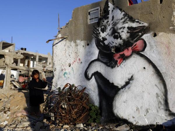 A Palestinian child stands next to a mural of a kitten on the remains of a house in the Gaza Strip town of Beit Hanun /AFP
