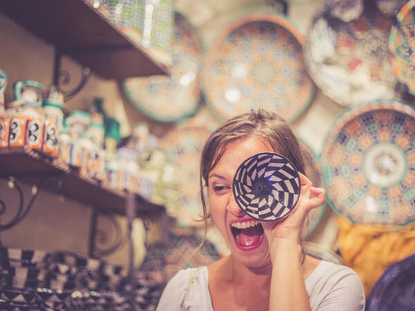 Happy girl playing with traditional arabic handcrafted, colorful decorated plates in Morocco Souk (Shutterstock/File Photo)