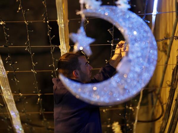 A Palestinian man decorates with lights near the entrance of the al-Aqsa mosque compound, in the old city of Jerusalem on May 4, 2019. AHMAD GHARABLI / AFP