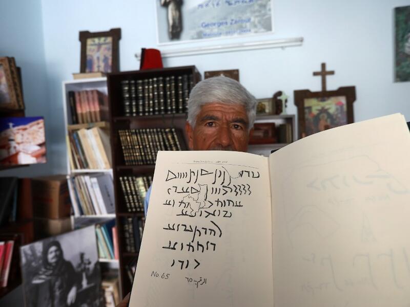 George Zaarour, a specialist in the Aramaic language, a notebook with Aramaic script written on it, in the Syrian mountain village of Maalula, in the Damascus region on May 13, 2019. LOUAI BESHARA / AFP