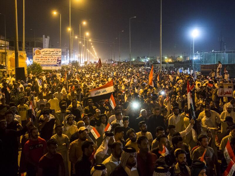 Iraqi followers of Shiite Muslim cleric Moqtada al-Sadr wave national flags and raise protest signs as they demonstrate in the southern city of Basra on May 24, 2019, against involvement in any conflict between Iran and the United States.  Hussein FALEH / AFP