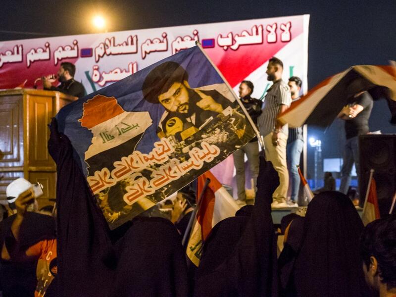 Iraqi followers of Shiite Muslim cleric Moqtada al-Sadr wave national flags and raise protest signs as they demonstrate in the southern city of Basra on May 24, 2019, against involvement in any conflict between Iran and the United States.  Hussein FALEH / AFP