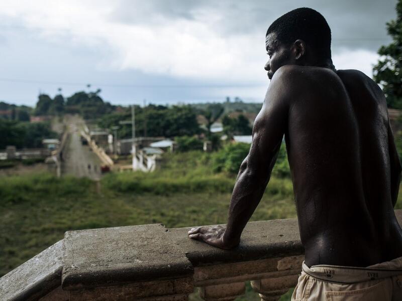An inhabitant waits in front of the abandoned hospital of the roca Agostinho Neto, an abandoned cocoa plantation of Sao Tome and Principe, on May 12, 2019.  Alexis HUGUET / AFP