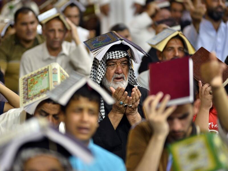 Shiite Muslims gather for the ritual prayer of Lailat al-Qadr, which marks the night in fasting month of Ramadan during which the Koran was first revealed to Prophet Mohammed in the seventh century, at the Imam Ali shrine in the central Iraqi holy city of Najaf on May 29, 2019.  Haidar HAMDANI / AFP