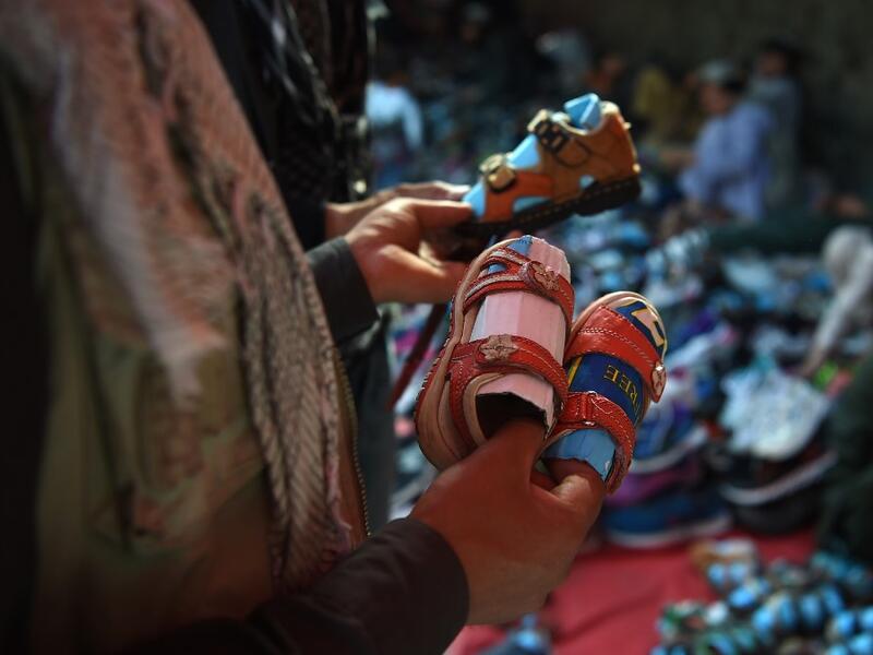 An Afghan man looks at sandals for children ahead of the Eid al-Fitr festival, which marks the end of Islamic holy month of Ramadan, at a roadside in Kabul on June 2, 2019. WAKIL KOHSAR / AFP