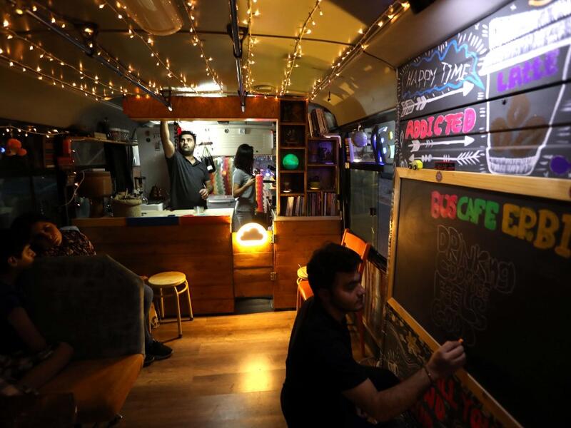 Young Iraqi Kurds work inside "The Bus Cafe Erbil" in Arbil, the capital of Iraq's Kurdish autonomous region, late on June 7, 2019, on the long weekend of the Eid al-Fitr holiday which marks the end of the Muslim holy month of Ramadan.  SAFIN HAMED / AFP