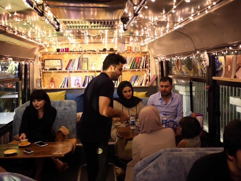 People have a drink at "The Bus Cafe Erbil" in Arbil, the capital of Iraq's Kurdish autonomous region, on June 7, 2019, on the long weekend of the Eid al-Fitr holiday which marks the end of the Muslim holy month of Ramadan.  SAFIN HAMED / AFP