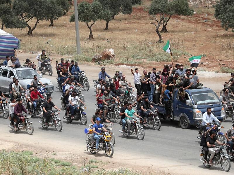 A convoy of Syrians follow the truck carrying the coffin of late rebel fighter Abdel-Basset al-Sarout on June 9, 2019, near the Bab al-Hawa crossing point, northwestern Syria, on the way to his funeral after crossing the border from Turkey where he was receiving treatment following his injury earlier this week. OMAR HAJ KADOUR / AFP