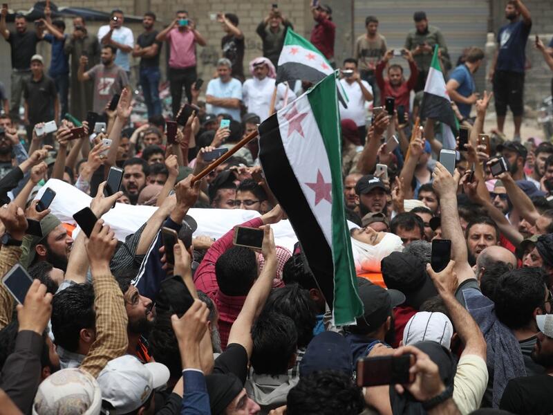 A picture taken on June 9, 2019 shows Syrians waving rebel flags during the funeral of late rebel fighter Abdel-Basset al-Sarout in al-Dana in Syria's jihadist-controlled Idlib region, near the border with Turkey. OMAR HAJ KADOUR / AFP
