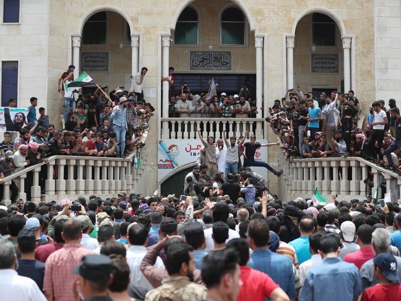 A picture taken on June 9, 2019 shows Syrians waving rebel flags and portraits of Abdel-Basset al-Sarout during the funeral of the late rebel fighter in al-Dana in Syria's jihadist-controlled Idlib region, near the border with Turkey. OMAR HAJ KADOUR / AFP